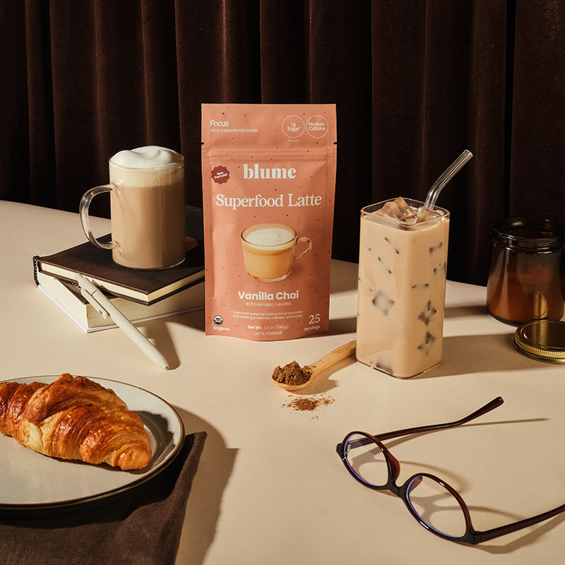 Blume Superfood Latte package with a cup of hot latte, iced latte, and croissant on a table.